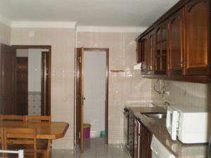 a kitchen with wooden cabinets and a table with a microwave at Lagar in Manta Rota