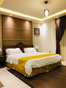 a bedroom with a large bed with a wooden headboard at شامة جدة للشقق المخدومة in Jeddah