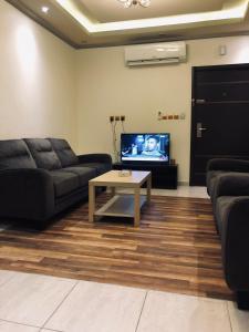 a living room with a couch and a table and a tv at Shamat Jeddah Furnished Units in Jeddah