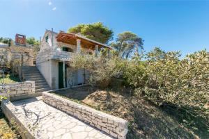 a house with a stone retaining wall and a yard at House Svjetlana in Postira