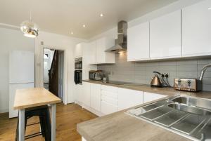 a kitchen with white cabinets and a sink at House for Families or Groups near Cardiff City Centre in Cardiff