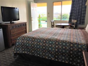 a bedroom with a bed and a flat screen tv at Ramblin Rose Motel in Kingman +15 photos