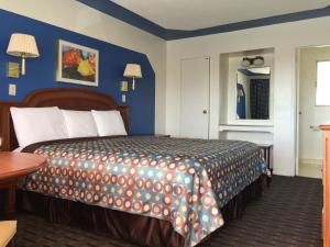 a bedroom with a large bed with a blue wall at Ramblin Rose Motel in Kingman