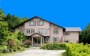 a large pink house with a driveway at Pension Candytuft in Karuizawa