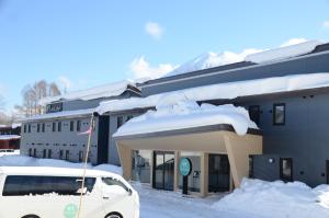 a white car parked in front of a building with snow at My Ecolodge in Kutchan