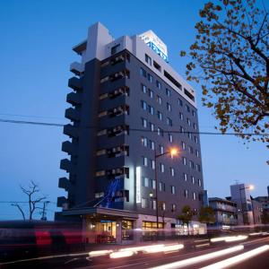 Un edificio alto en una calle de la ciudad por la noche. en New Station Hotel Premiere, en Isahaya