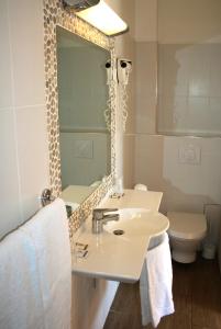 La salle de bains est pourvue d'un lavabo, d'un miroir et de toilettes. dans l'établissement Hôtel Colombo- Porto Corse, à Porto Ota