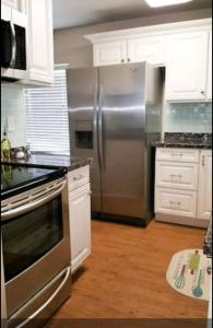 a kitchen with a stainless steel refrigerator and white cabinets at La Casita in Phoenix