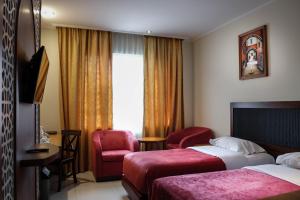 a hotel room with two beds and a chair and a window at Onih Hotel in Bogor
