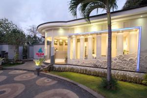 un grande edificio bianco con una palma di fronte di The Xotic Jimbaran Bali a Jimbaran