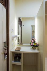 een badkamer met een wastafel met een spiegel en bloemen bij The Xotic Bali in Jimbaran