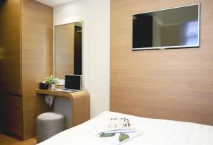 ein Hotelzimmer mit einem Bett und einem TV an der Wand in der Unterkunft Bridal Tea House Hotel - Yaumatei in Hongkong