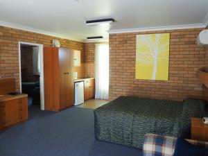 um quarto com uma cama e uma parede de tijolos em Cudgegong Valley Motel em Mudgee