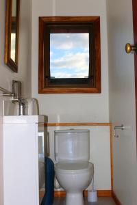 Baño con aseo y ventana encima en The Beach Lodge, en Onekaka