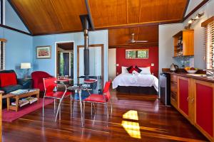 ein Wohnzimmer mit einem Bett und eine Küche mit roten Stühlen in der Unterkunft Rosebrook Cottages in Maleny