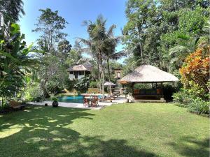 a backyard with a swimming pool and a house at Villa Alamanda in Ubud