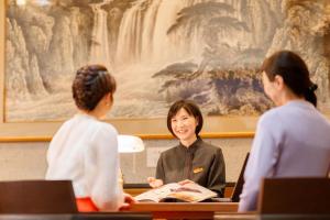 Eine Frau, die mit zwei Frauen am Schreibtisch sitzt. in der Unterkunft Hotel Shiki no Yakata Nasu in Nasu