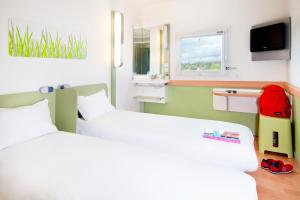 een hotelkamer met 2 bedden en een raam bij ibis budget Narbonne Sud A9/A61 in Narbonne