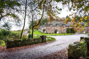 an old stone house with a stone wall and a driveway at Dunnottar Woods House in Stonehaven
