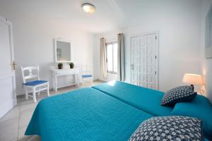 a white bedroom with a blue bed and a chair at Punta N 5 - Vivienda vacacional in Santiago del Teide +43 photos