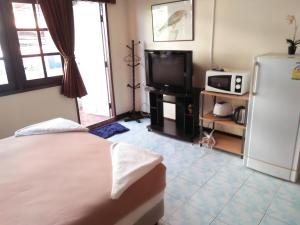 a bedroom with a bed and a refrigerator and a tv at Stefan's Guesthouse in Jomtien Beach