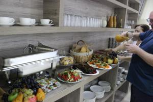 two people standing in a buffet line with food at Hotel Comfort in Kutaisi