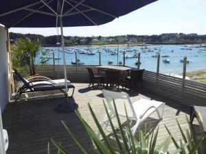 a deck with a table and chairs and an umbrella at Hôtel des Rochers in Perros-Guirec