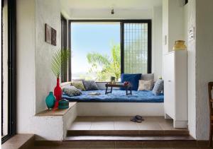 a window seat in a room with a view of the ocean at Bungalow 89 by StayVista - A hill-view villa adorned with eclectic interiors for a truly unique & captivating stay in Lonavala