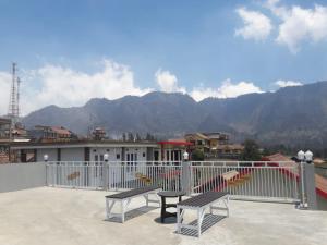 two benches sitting on a balcony with mountains in the background at Bromo Otix Guest House in Bromo