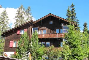 a large wooden house with a balcony at Chalet Waldesruh 3 Zimmerwohnung in Arosa
