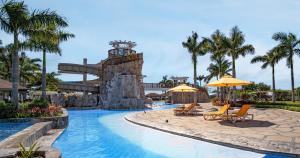a pool at the resort with chairs and umbrellas at Crusoe Cabins Casobe in Calatagan