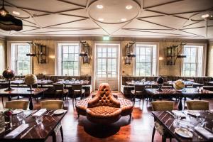 a restaurant with tables and chairs and a couch in a room at Stoke Place- Part of the Cairn Collection in Slough