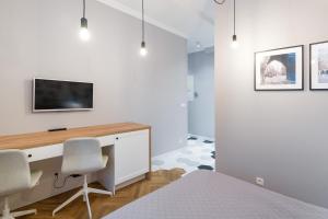 a bedroom with a desk and a tv on a wall at Welcome Apartments - Old Town in Krakow