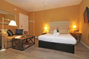マラガにあるDel Parque Flats Suite Malaguetaのベッドルーム(大型ベッド1台、ソファ付)