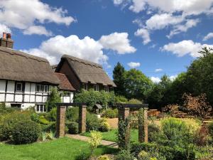 una casa antigua con techo de paja y jardín en Old Hunters Lodge en Whipsnade