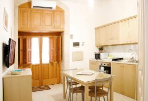kuchnia z drewnianymi szafkami i stołem z krzesłami w obiekcie Rosa Holiday Home w Syrakuzach