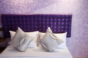 1 cama con almohadas blancas y cabecero púrpura en Nang-an Inn Resort, en Suratthani