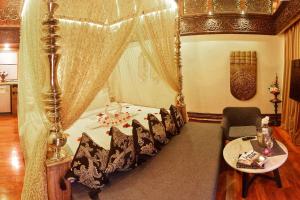 a bedroom with a canopy bed with chairs and a table at Sawasdee Village in Kata Beach