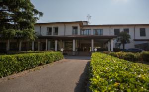 un gran edificio blanco con arbustos delante en Hotel Internazionale Gorizia, en Gorizia