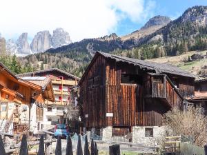 an old wooden building with mountains in the background at Tabià Elisa in Campitello di Fassa