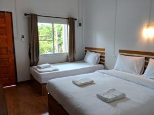 two twin beds in a room with a window at Maruay in Suratthani