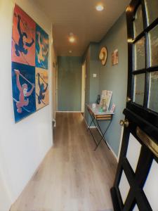 un couloir avec une table et des peintures sur les murs dans l'établissement B&B Little Miss Sunshine, à Zandvoort