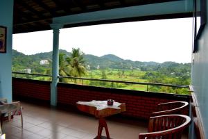 un balcone con tavolo e sedie e vista di Rathna Gems Halt a Ratnapura