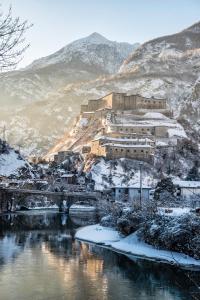 a building on top of a mountain with a river at Hotel Cavour Et Des Officiers in Bard