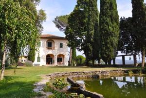 une grande maison avec un étang en face de celle-ci dans l'établissement "Alle Montanine" Villa Poggio, à Impruneta
