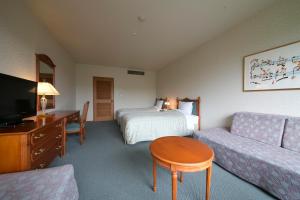 een hotelkamer met een bed en een bank bij Sky Park Hotel in Chino