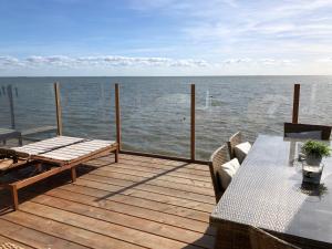 a wooden deck with a table and bench on the water at Vakantie Villa Markermeer in Bovenkarspel