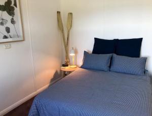 a bedroom with a blue bed with a lamp on a table at The Boat House in Strahan