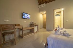 a room with a bed and a tv on the wall at Tetirah Boutique Hotel in Ubud