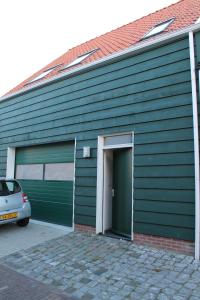 un edificio verde con una puerta y un coche en Het Bakkersschuurtje, en Colijnsplaat